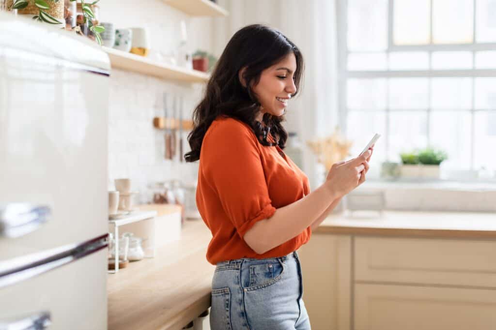 Woman browsing phone in a cozy kitchen