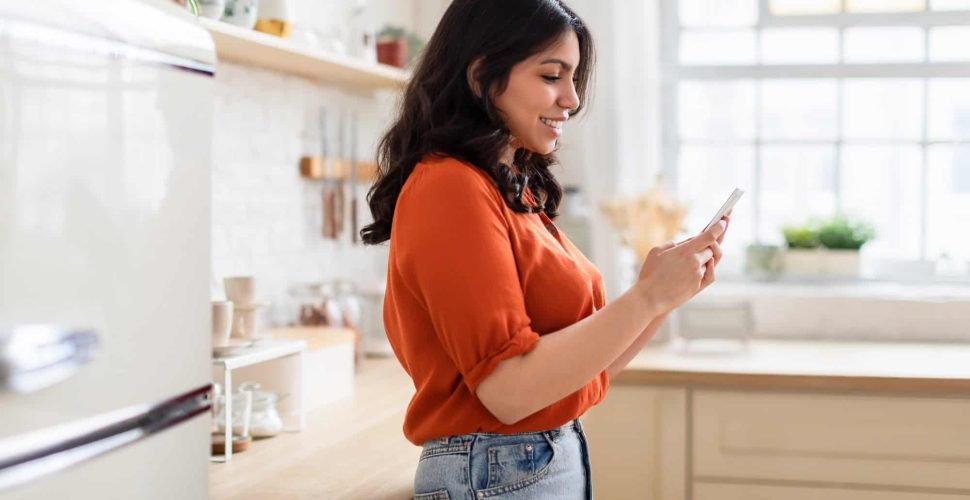 Woman browsing phone in a cozy kitchen